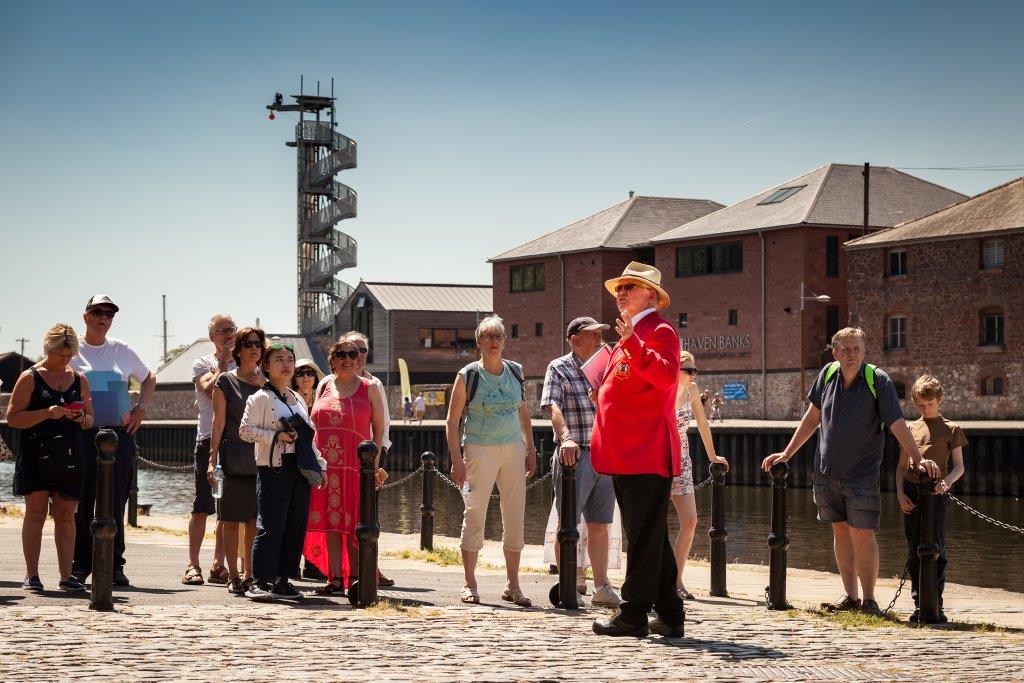 Red coat tour guide with group on Exeter Quay